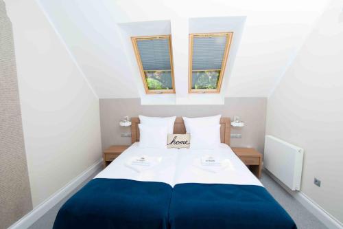 a bedroom with a blue and white bed with two windows at Hudson in Koszalin