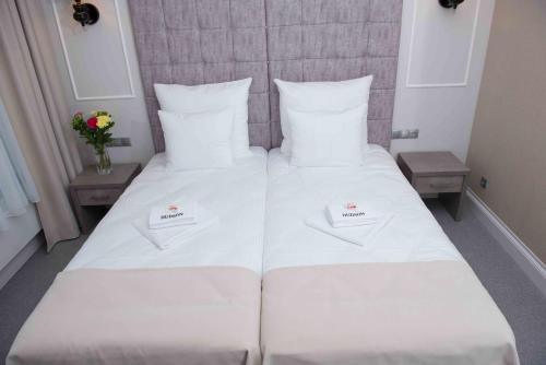 a large white bed with two white towels on it at Hudson in Koszalin