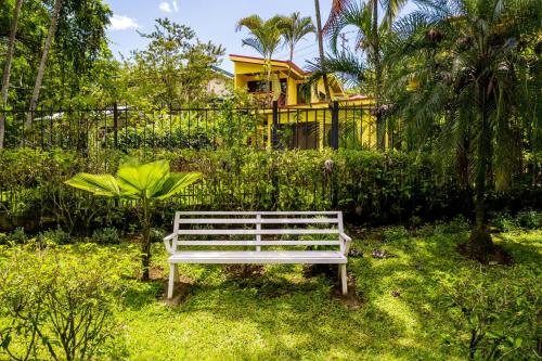a white bench sitting in the grass in front of a house at La Terraza Guest House B&B in Grecia