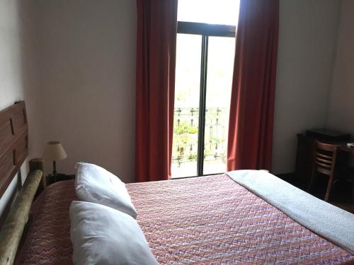 a bedroom with a bed and a window with red curtains at San Isidro Hotel in Mercedes