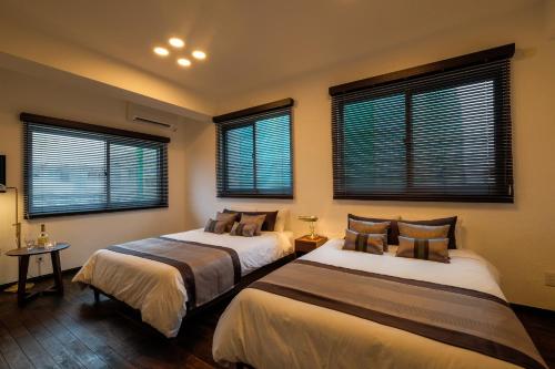 two beds in a room with two windows at Ginowan - House / Vacation STAY 46771 in Ginowan