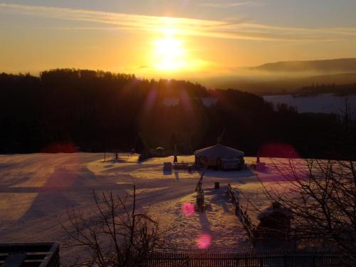 a sunset over a snowy field with the sun in the sky at Hotel Gasthof zur Post in Winterberg