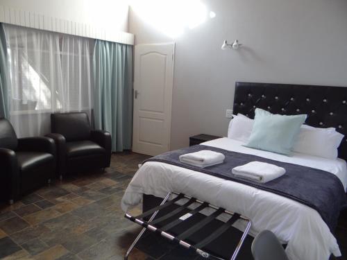 a bedroom with a large bed with a chair and a window at CREDO Guest House in Bloemfontein