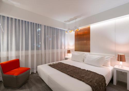 a bedroom with a large bed and a red chair at 45 by Director in Santiago
