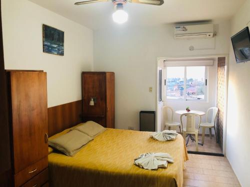 a bedroom with a bed and a table and a window at Apart-Hotel Gibert's House in Villa Carlos Paz