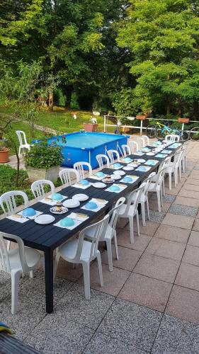 een lange tafel met witte stoelen en een zwembad bij CROTTO CARACO APPARTAMENTI BUNGALOW CHALET in Porlezza