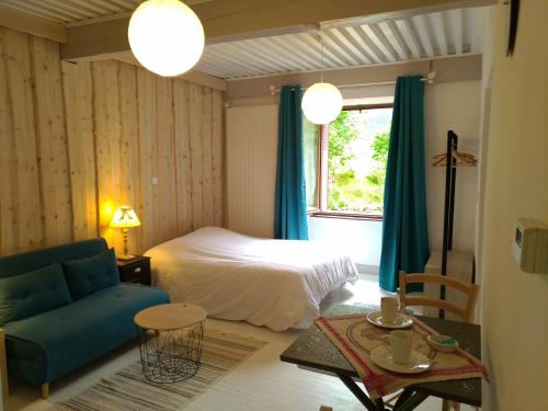 a bedroom with a bed and a blue couch at le Mas du lac - spa et détente in Monestier-dʼAmbel