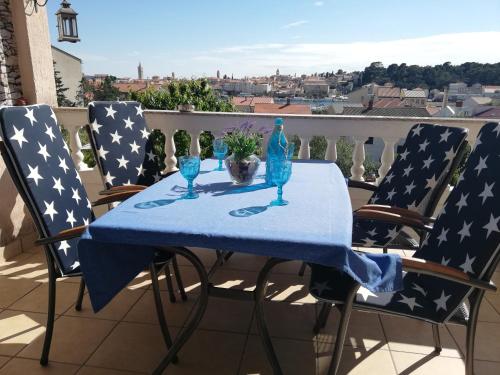 a table with two chairs with a blue table cloth and glasses at Apartmani Paula in Rab