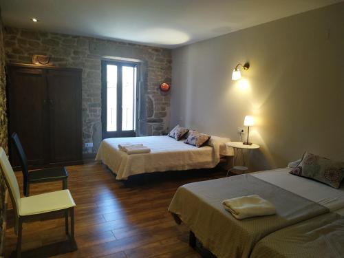 una habitación de hotel con dos camas y una silla en La Teodora, en Aldeadávila de la Ribera