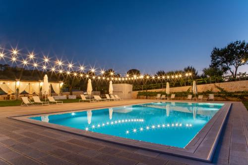 una piscina notturna con sedie e luci di Ottolire Resort a Locorotondo