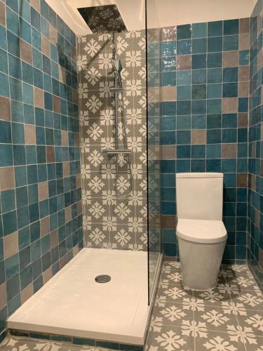 a bathroom with a shower with a toilet and tiles at Auberge du Château in Margon