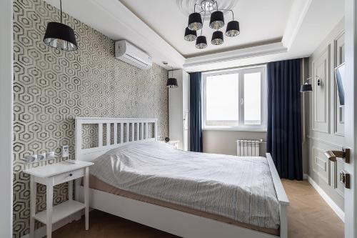 a bedroom with a white bed and a window at Апартаменты Архитектор на набережной in Nizhnevartovsk