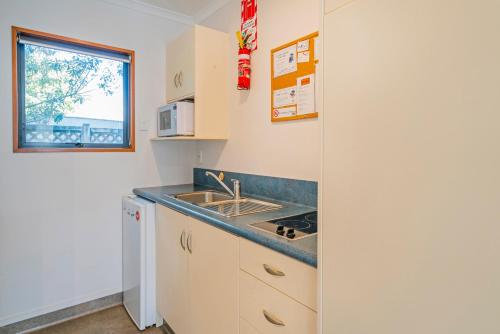 a small kitchen with a sink and a window at Bayside Motel Whitianga in Whitianga