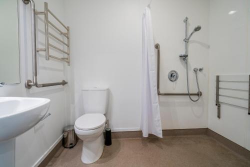 a bathroom with a toilet and a sink and a shower at Bayside Motel Whitianga in Whitianga