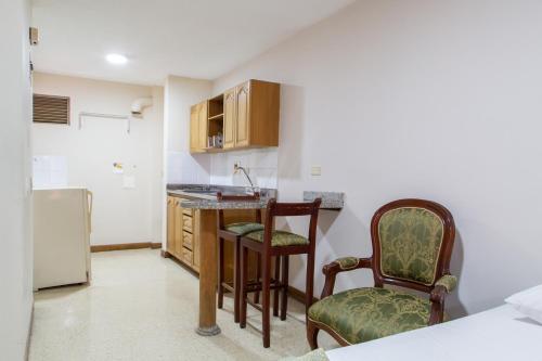 a kitchen with a desk and two chairs and a refrigerator at Hotel San Pedro del Fuerte in Medellín