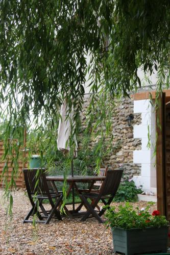 a picnic table and two chairs under a tree at Les chaumières du Chêne in Pouillé