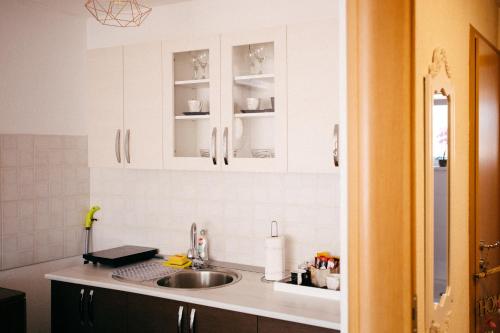 a kitchen with white cabinets and a sink at Lux Apartment I Prijedor in Prijedor