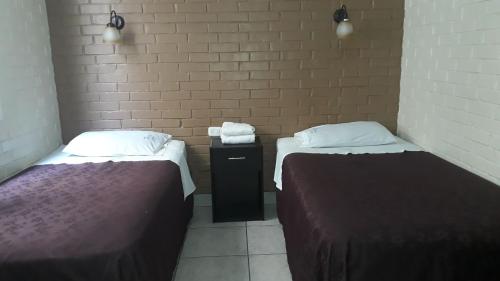 Habitación con 2 camas y pared de ladrillo en Hotel Capri en Guatemala