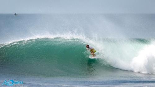 a man riding a wave on a surfboard in the ocean at Las Dunas Surf Resort in Aposentillo