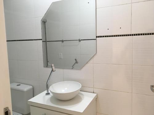 a white bathroom with a sink and a mirror at Casa edícula no centro com Smart TV in Joinville