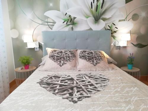 a bedroom with a bed with a heart pillow and flowers at Ático BELLAVISTA con visita a bodega y cata de vinos 4 habitaciones dobles 2 baños completos in Tudela