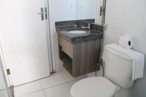 Łazienka z białą toaletą i umywalką w obiekcie Apto 166 Lacqua diRoma V - Sacada em frente a Piscina de Ondas, com roupa de Cama, camareira e garagem w mieście Caldas Novas