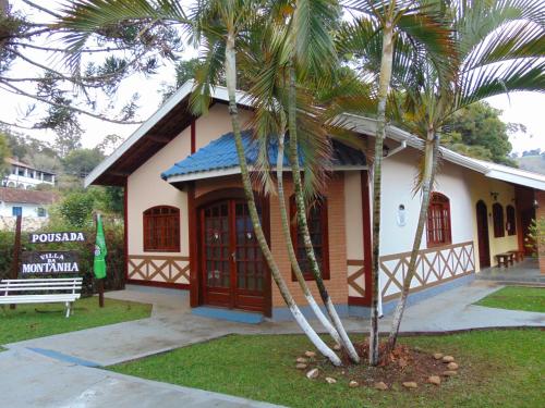 a small house with palm trees in front of it at Pousada Villa Da Montanha in São Bento do Sapucaí