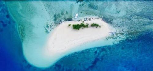 a small white island in the water in the ocean at Oasis Resthouse in San Agustin