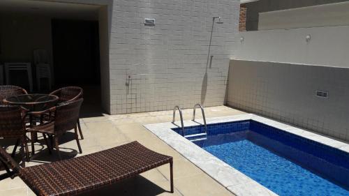 - une piscine avec une table et des chaises à côté dans l'établissement Apartamento Edifício Edécio Lopes, à Maceió