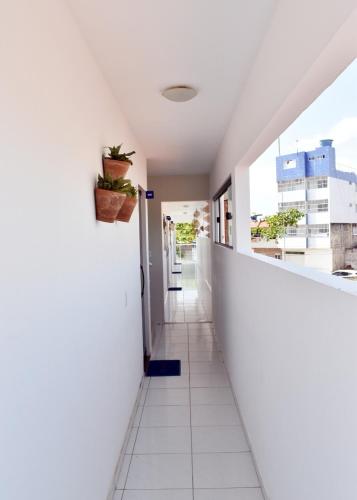 a corridor of a room with white walls and a window at Suítes&Flats MarBello in Maragogi