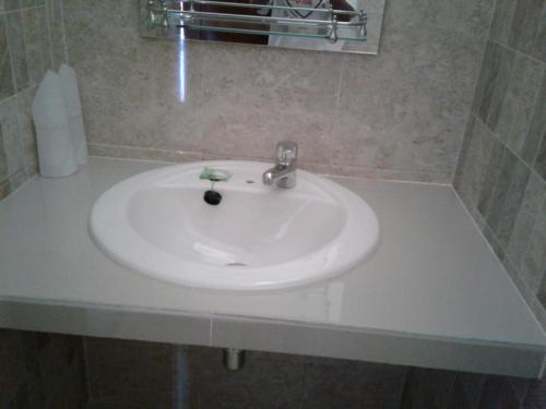 lavabo blanco en el baño con espejo en Toraja Torsina Hotel en Rantepao