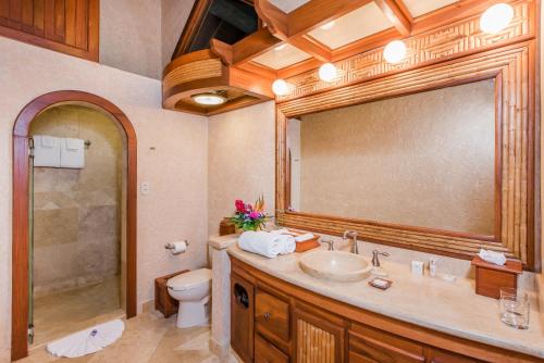 a bathroom with a sink and a toilet and a mirror at The Springs Resort & Spa at Arenal in Fortuna