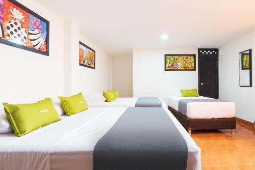 a hotel room with two beds with green pillows at Ayenda 1045 Boutique Aeropuerto in Bogotá