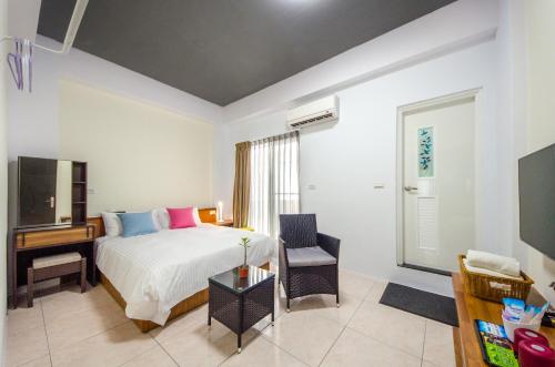 1 dormitorio con 1 cama, escritorio y TV en Chi's House B&B, en Taitung
