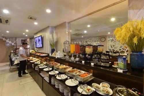 a man standing in front of a buffet line with food at Hanoi Eternity Hotel in Hanoi