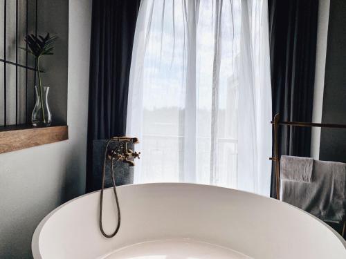 a white bath tub in front of a window at Hotel Gahn Khao Lak in Khao Lak