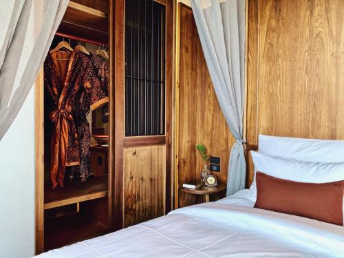 a bedroom with a bed and a wooden wall at Hotel Gahn Khao Lak in Khao Lak
