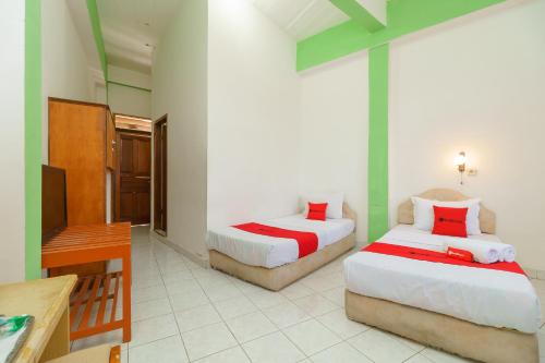 a hotel room with two beds and a television at RedDoorz @ Tuktuk Danau Toba in Tuk Tuk