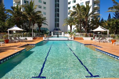 a large swimming pool with chairs and a building at Carmel by the Sea in Gold Coast