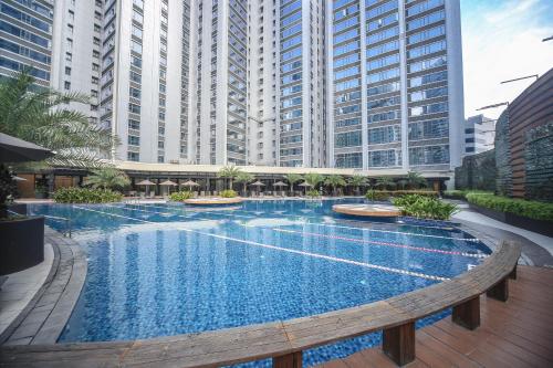 una gran piscina con edificios altos en el fondo en The Alpha Suites en Manila