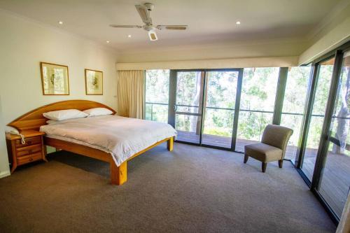 a bedroom with a bed and a chair and windows at ARUM in Margaret River Town
