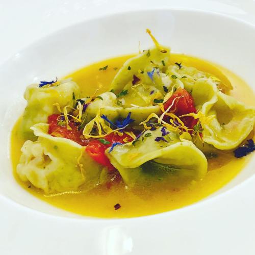 a white bowl of food with yellow sauce and vegetables at Relais Villa Giuliana in Licata