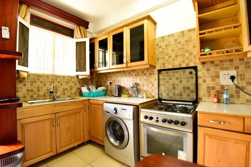 a kitchen with a stove and a dishwasher at Crane Serviced Apartments in Entebbe