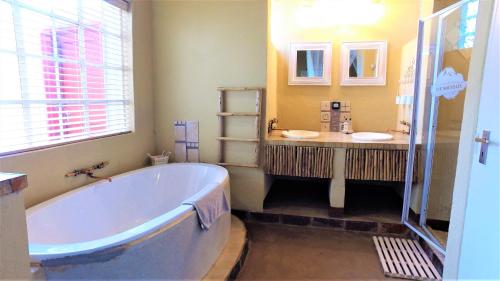 a large bathroom with a tub and two sinks at Blyde Mountain Country House in Hoedspruit