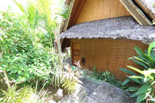 a small building with a thatch roof at Palau Plantation Resort in Koror