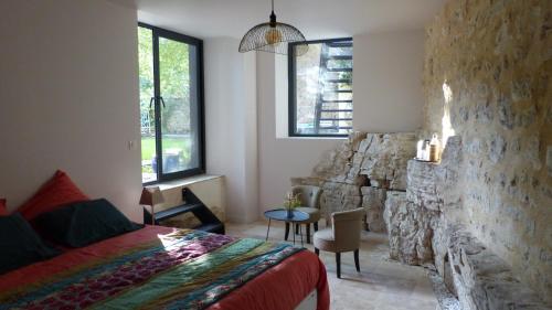 a bedroom with a bed and a stone wall at Les Jardins Sauvages in Cabrerets
