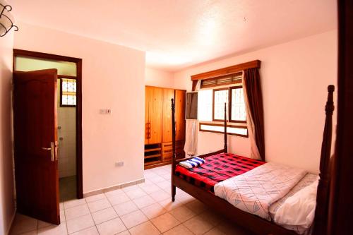 a bedroom with a bed and a window at Crane Serviced Apartments in Entebbe