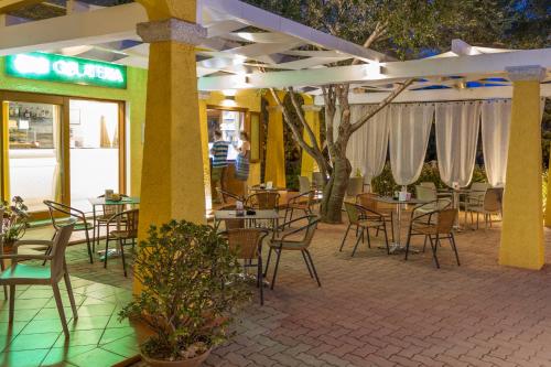 un patio con tavoli e sedie in un ristorante di Hotel Lu Pitrali a San Teodoro
