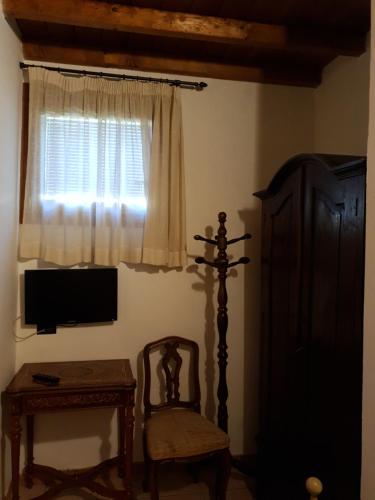 a room with a chair and a television and a window at La Baita in Boario Terme
