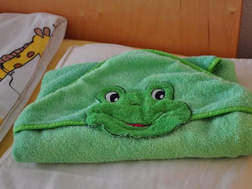 a green towel with a face on a bed at Bunte Burg in Ebenweiler